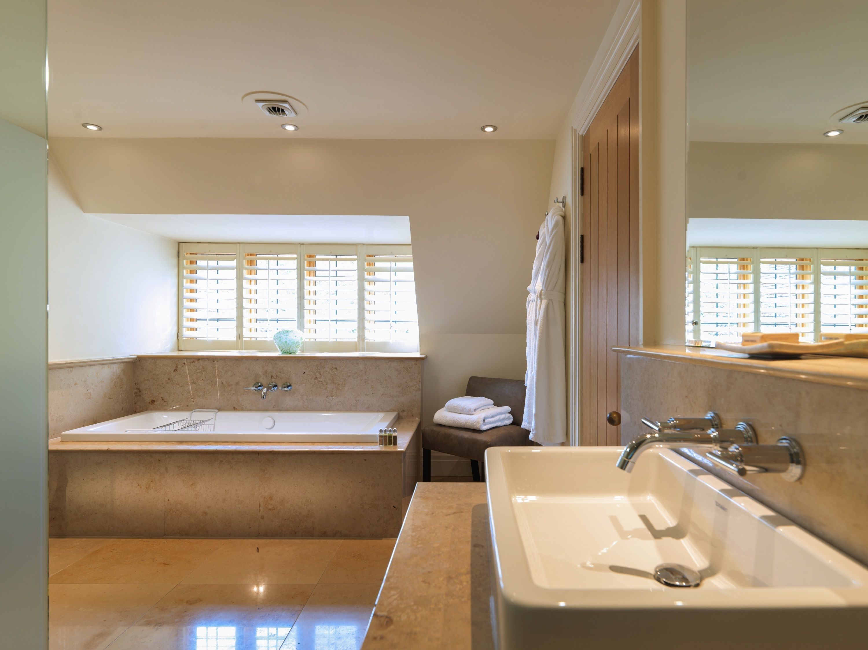A bathroom with a bathtub, a sink, and a window with blinds.