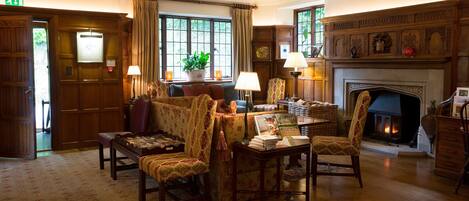 A traditional library with wooden bookshelves, a fireplace, and comfortable seating areas.
