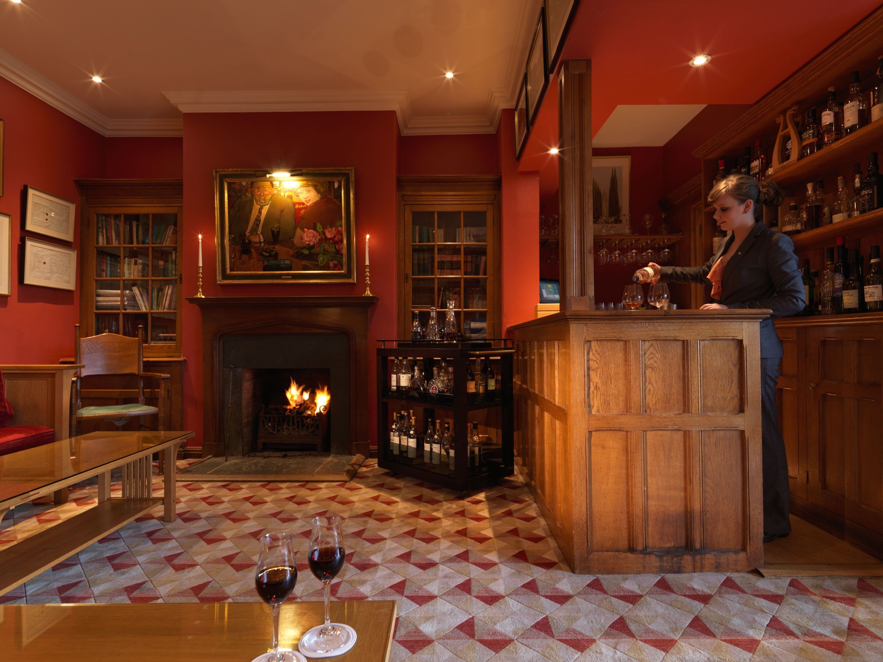 A bar area with a fireplace, bookshelves, and a bar counter.