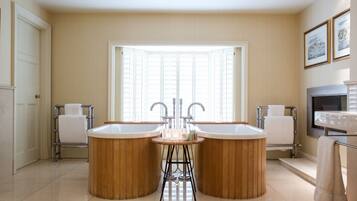 A bathroom with two large wooden tubs, a sink, and a window providing natural light.