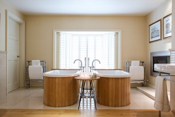 A bathroom with two large wooden tubs, a sink, and a window providing natural light. - Gidleigh Park (Newton Abbot)