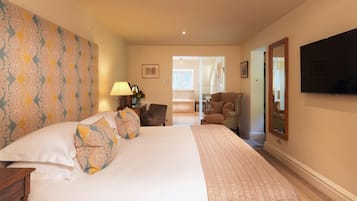 A hotel room with a large bed, a desk, a chair, a TV, and a mirror.
