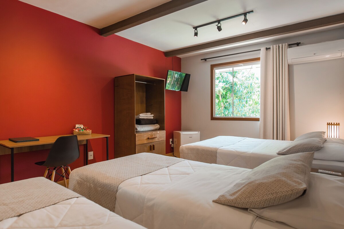 A hotel room with two beds, a desk, a TV, and a window with curtains.