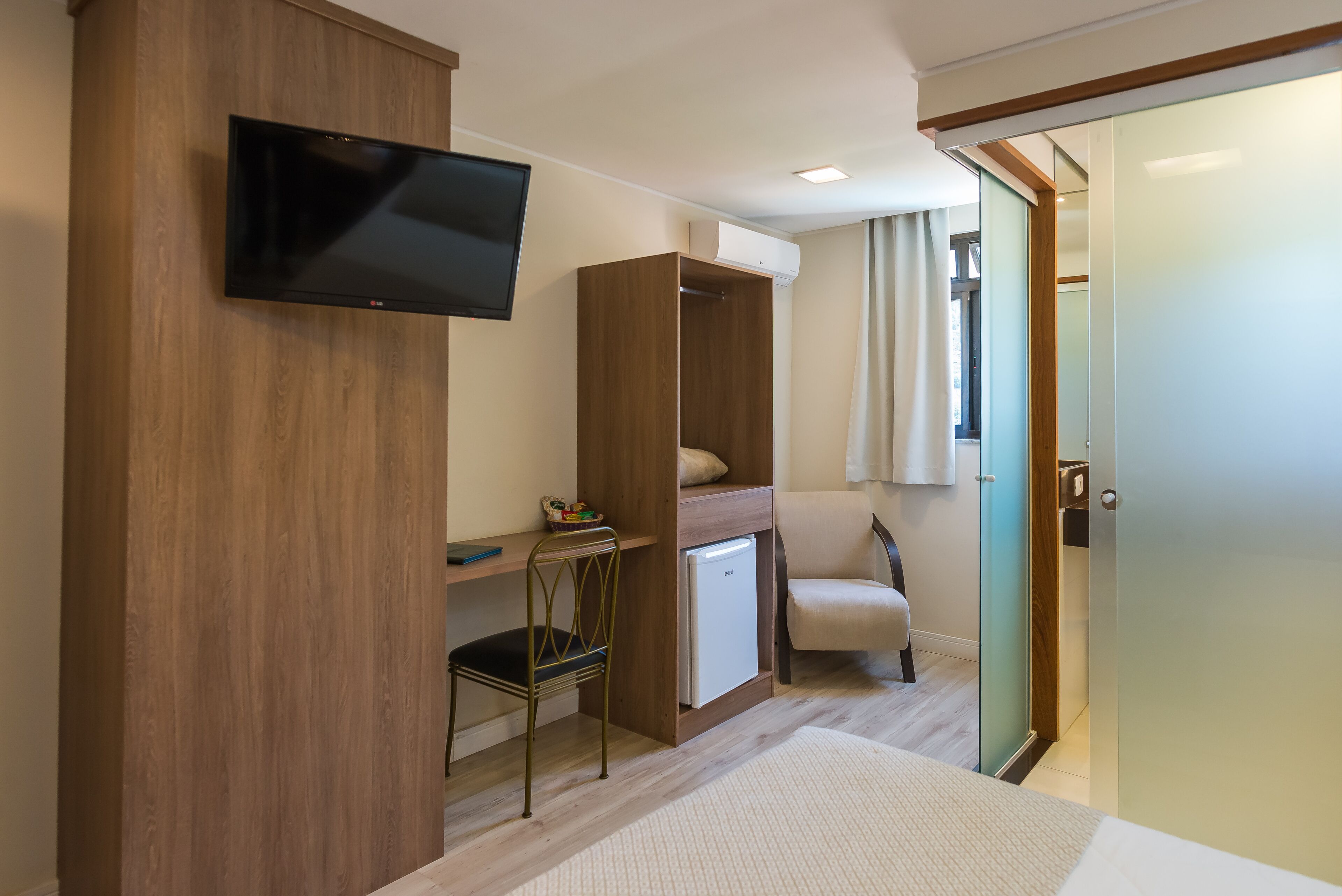 A bedroom with a bed, a desk, a chair, a television, and a wardrobe.