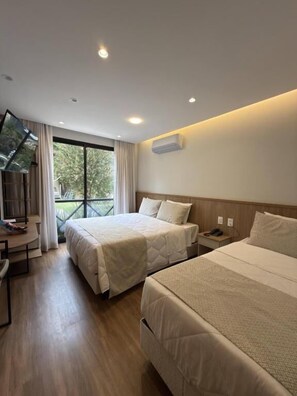 A hotel room with two beds, a desk, and a TV.