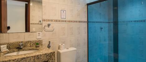 Un baño con encimera de granito, inodoro y ducha con mampara de vidrio.