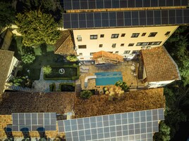Vista aérea de un edificio con paneles solares, piscina y jardín.