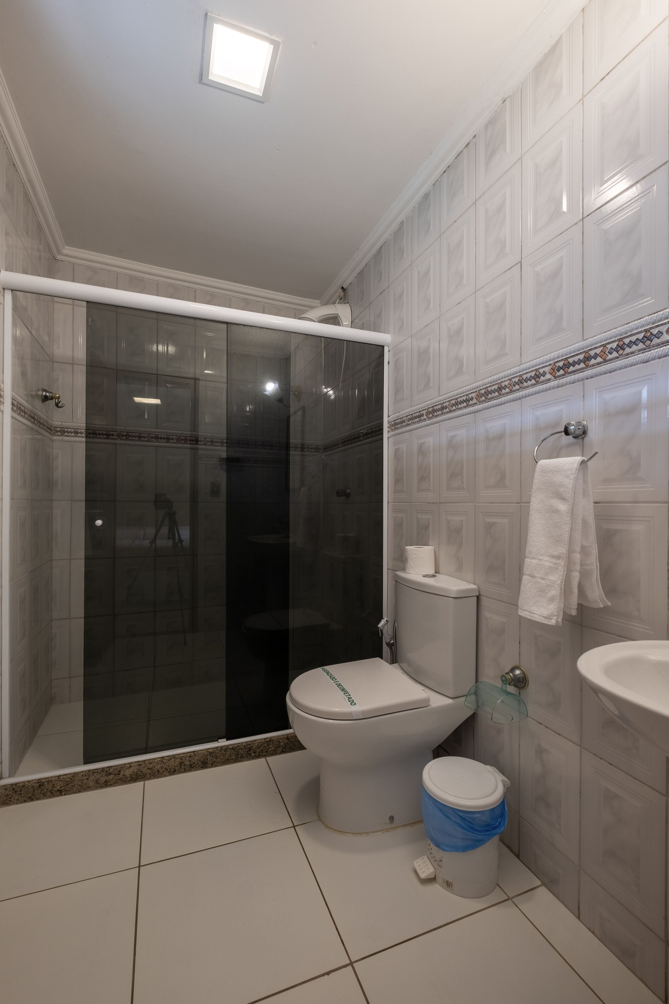 A bathroom with a glass-enclosed shower, a toilet, and a sink.