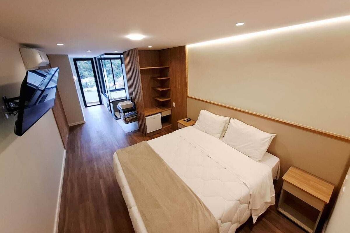 A modern hotel room with a large bed, a desk, and a TV.