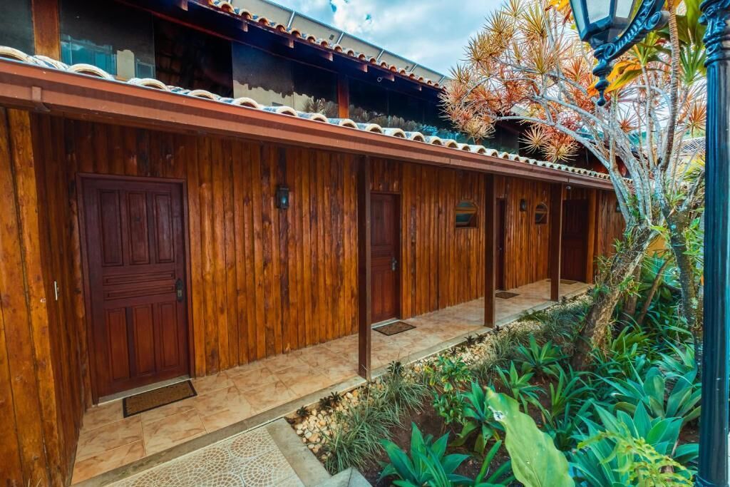 A wooden building with a covered porch and a small garden area with plants.