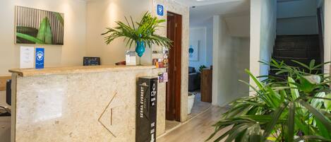 A hotel reception area with a marble counter, a blue sign, and a potted plant.