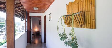 A corridor with a wooden ceiling, a bamboo wall decoration, and a hanging plant.