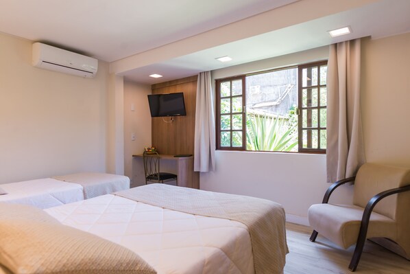 Una habitación de hotel con dos camas, televisión, escritorio y ventana con cortinas.