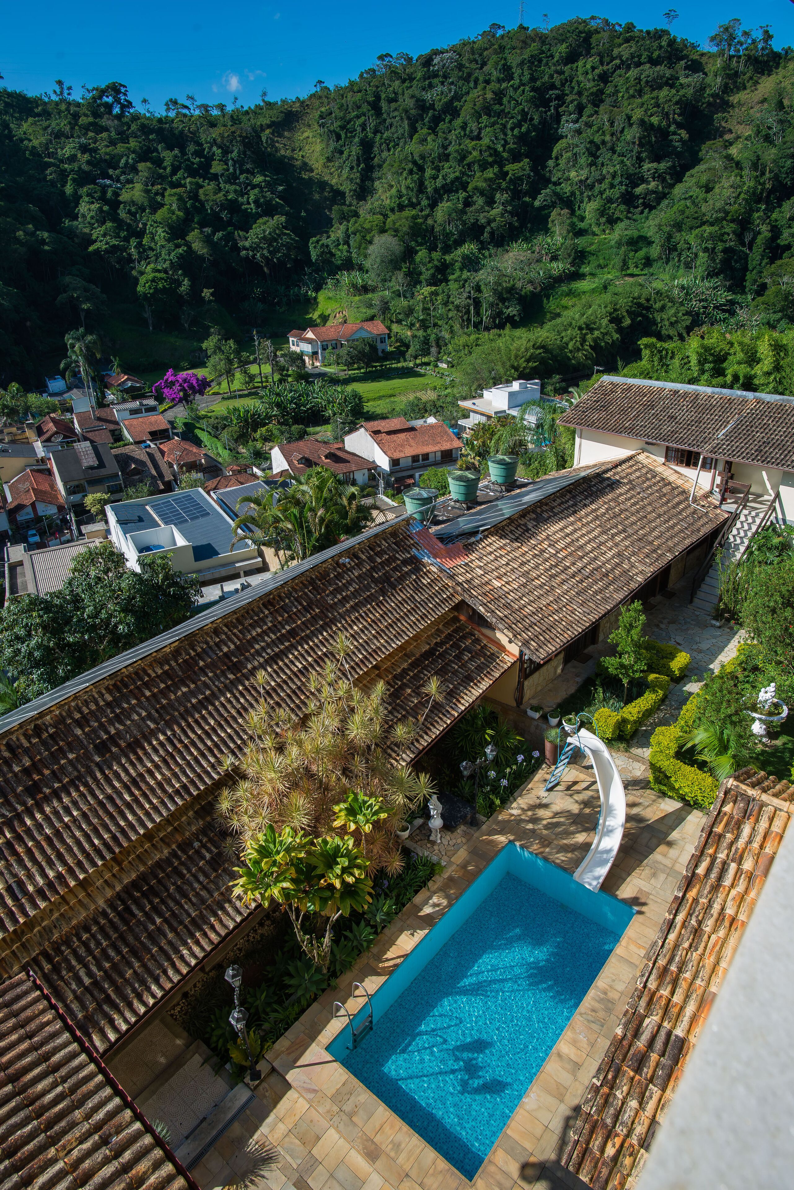 A residential area with a swimming pool, tiled roofs, and lush greenery.
