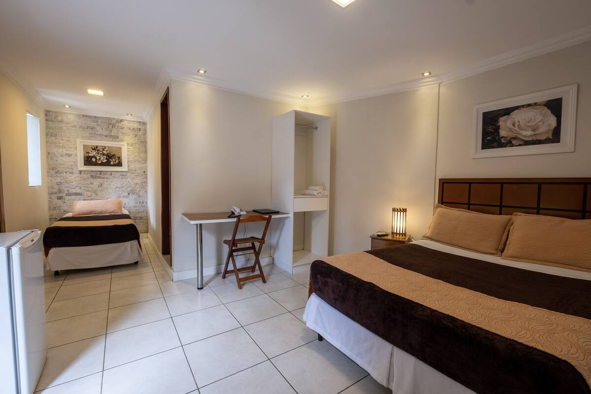 A hotel room with a bed, a desk, a chair, a wardrobe, and a bathroom.