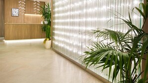 A modern reception area with a wooden reception desk, a clock, and a decorative wall with vertical lines. - Hotel Atlantic (Gabicce Mare)