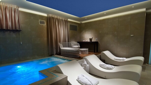 A modern spa area with a pool, lounge chairs, and a small seating area. - Hotel Atlantic (Gabicce Mare)