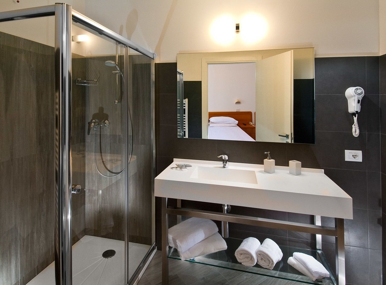 A modern bathroom with a glass-enclosed shower, a white sink with two basins, and a mirror above the sink.