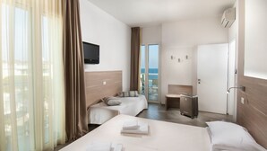 A hotel room with two beds, a TV, a desk, and a view of the sea. - Hotel Atlantic (Gabicce Mare)