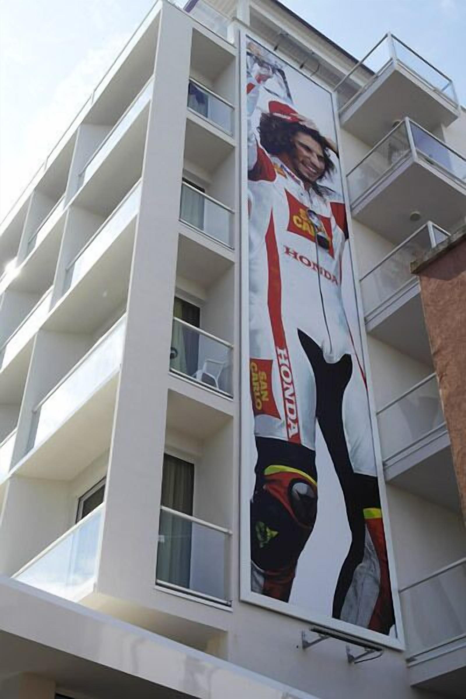 A multi-story building with balconies and a large advertisement featuring a motorcycle and the Honda logo.