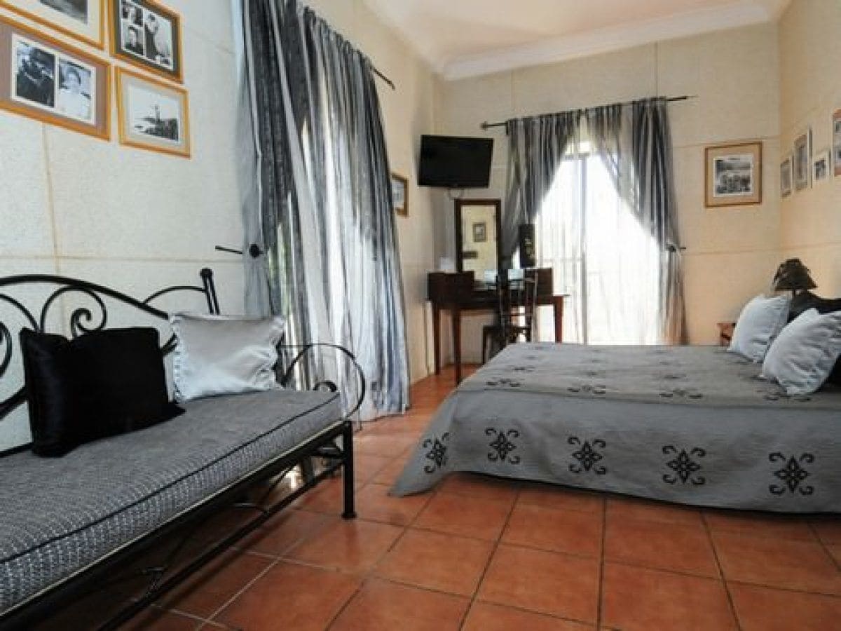 A bedroom with a bed, a sofa, a desk, and a television.
