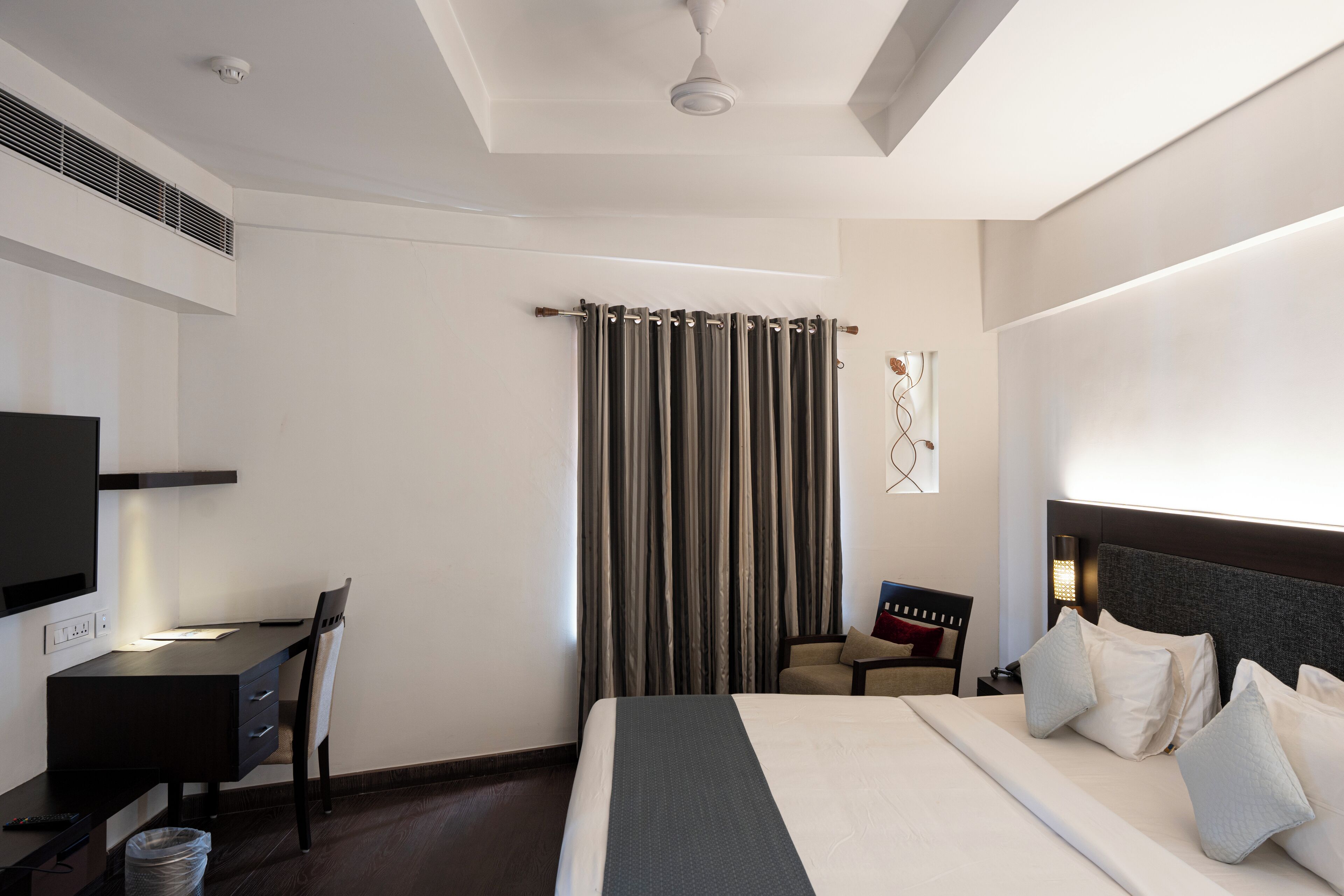 Una habitación de hotel moderna con una cama grande, un escritorio, una silla y un televisor.