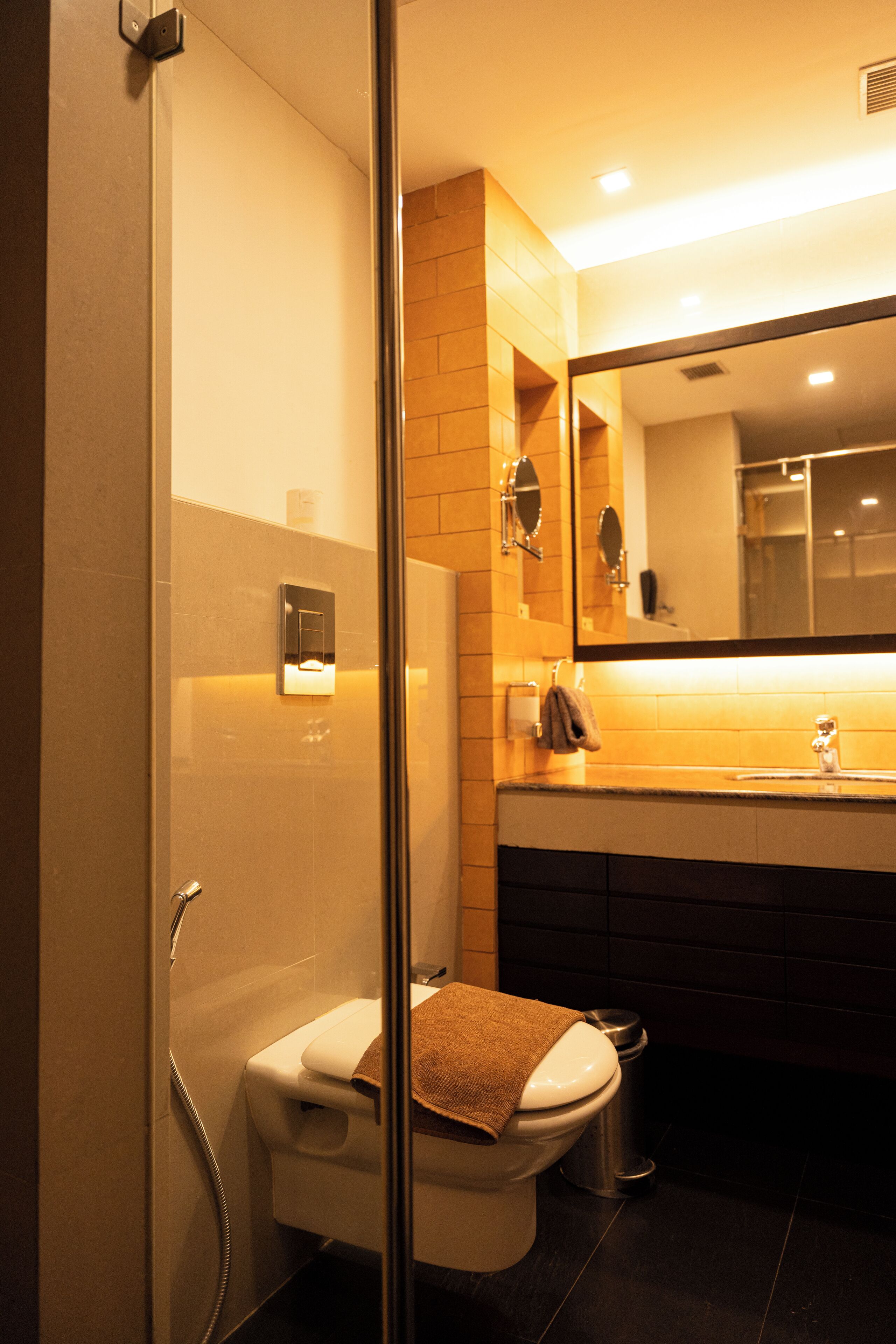 Un baño moderno con cabina de ducha de vidrio, inodoro, lavabo y espejo.