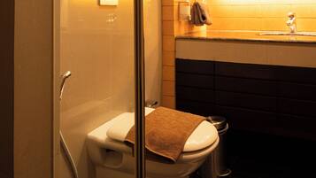 Un baño moderno con cabina de ducha de vidrio, inodoro, lavabo y espejo.