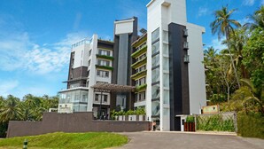 A modern hotel with multiple floors, large windows, and a well-maintained garden area. - Copper Folia (Kozhikode)