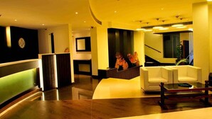A modern lobby with a reception desk, seating area, and a staircase. - Copper Folia (Kozhikode)