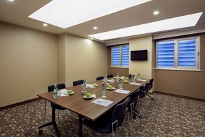 A conference room with a long table, chairs, water bottles, and a flat-screen TV. - Hampton by Hilton Gaziantep (Gaziantep)