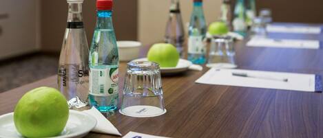 A conference table with water bottles, green apples, and documents.