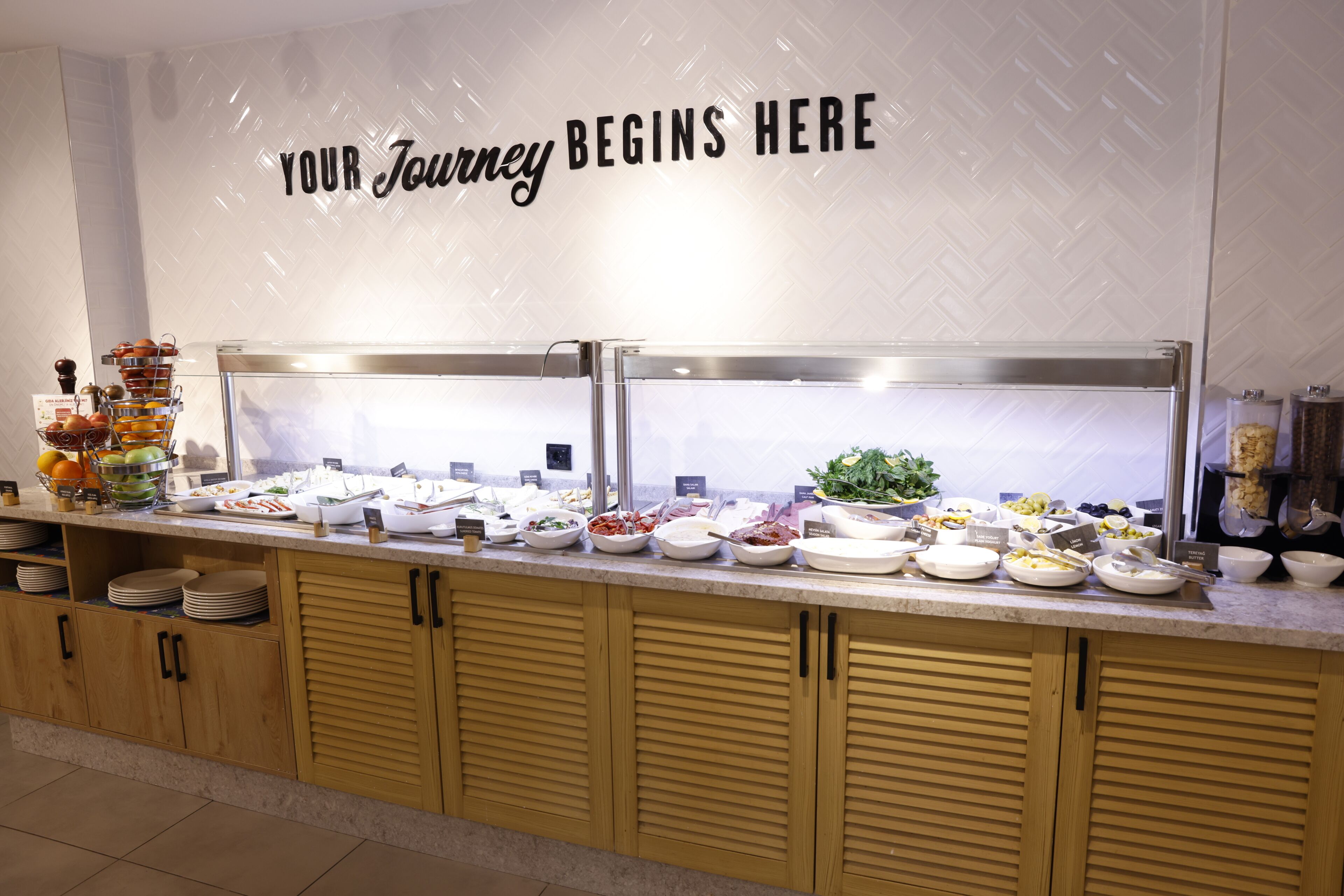 A buffet with various food items and a sign that reads 'YOUR Journey Begins Here'.