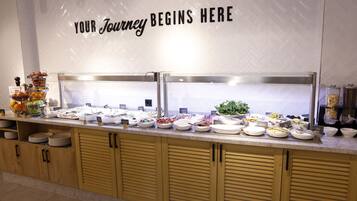A buffet with various food items and a sign that reads 'YOUR Journey Begins Here'.