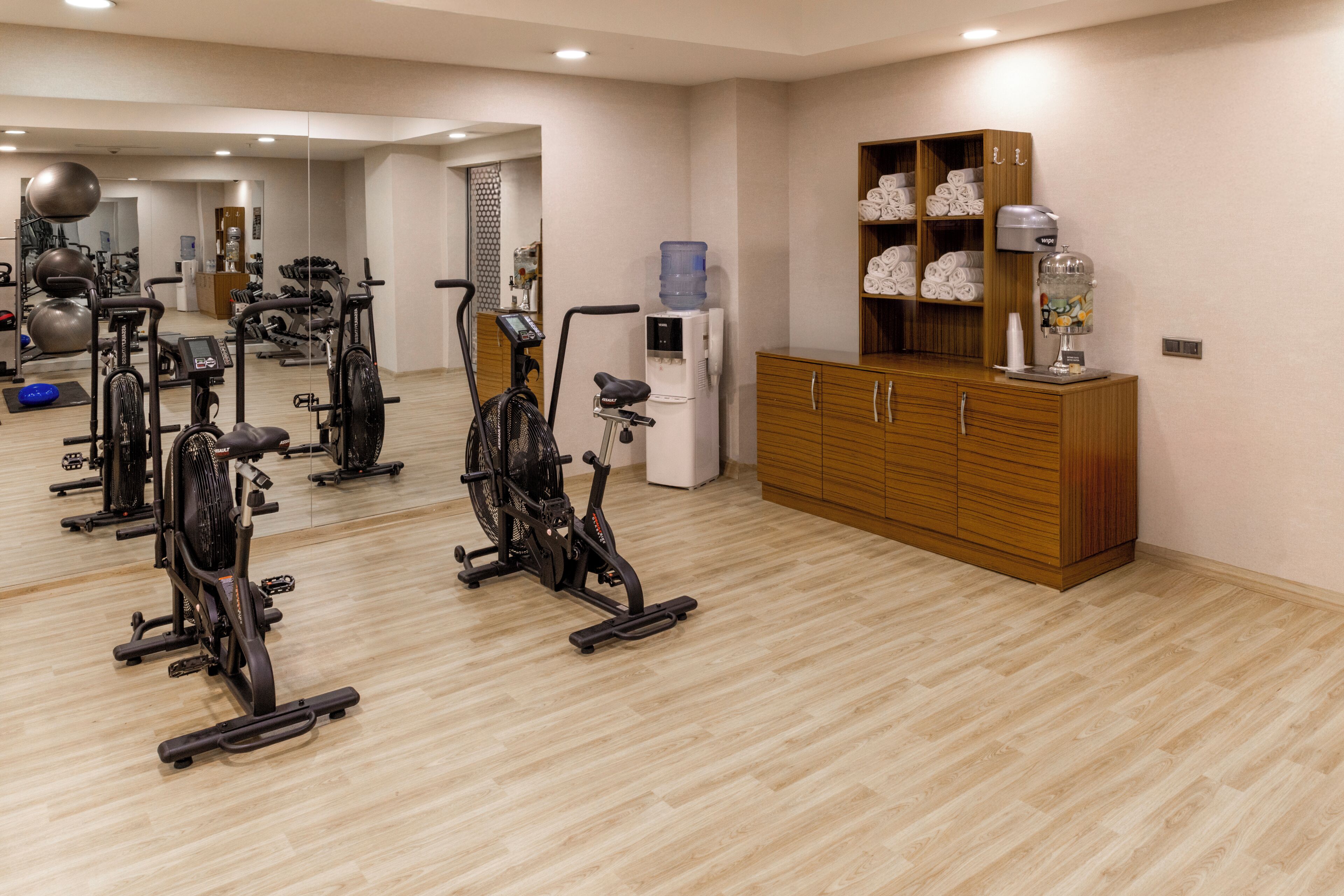 A gym with stationary bikes, a water dispenser, and a cabinet with towels.