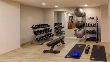 A gym with exercise equipment, including dumbbells, kettlebells, and exercise balls.