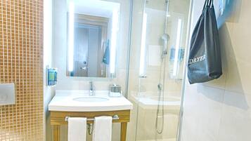 A modern bathroom with a glass-enclosed shower, a sink with a mirror, and a toilet.