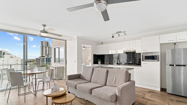 A modern apartment with a living area, kitchen, and balcony with city views. - Direct Collective - Pavilion and Governor on Brookes (Bowen Hills)