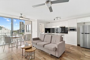 Un apartamento moderno con sala de estar, cocina y balcón con vistas a la ciudad.