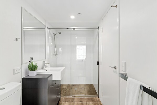 Un baño moderno con ducha, lavamanos e inodoro.