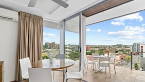 A modern room with a large balcony, a round table with chairs, and a city view. - Direct Collective - Pavilion and Governor on Brookes (Bowen Hills)