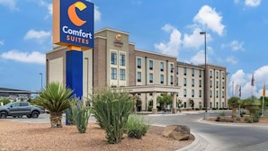Un hotel Comfort Suites con un llamativo letrero azul, fachada de ladrillo y un área de entrada cubierta.