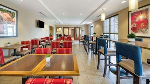 Un restaurante espacioso con varias zonas de comedor, incluyendo cabinas y mesas. Hay luces en el techo y amplias ventanas que brindan luz natural.