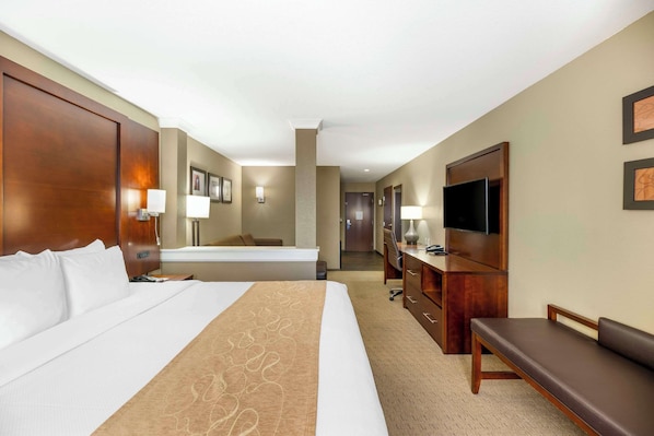 A hotel room with a large bed, a desk with a computer, a TV, and a bench. - Comfort Suites Carlsbad (Carlsbad)