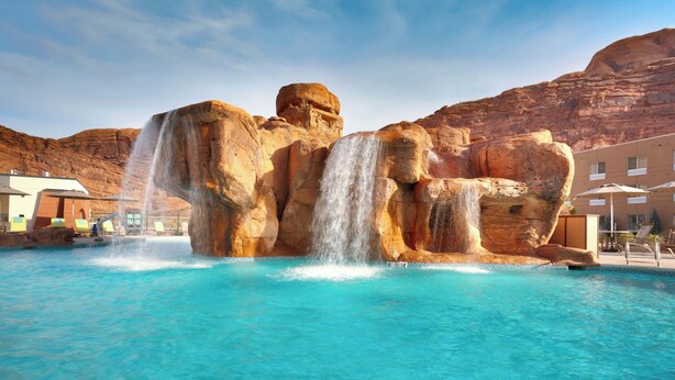 A pool with a waterfall feature, surrounded by a mountainous landscape. - Fairfield by Marriott Inn & Suites Moab (Moab)