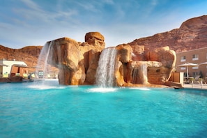 Une piscine agrémentée d’une cascade, entourée d’un paysage montagneux.