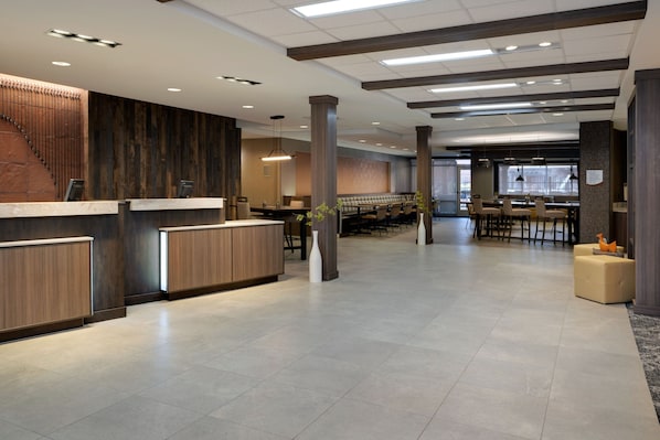 A spacious lobby with a reception desk, seating area, and a staircase.