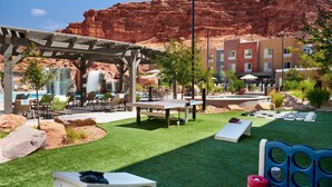 A pool area with a pergola, lounge chairs, and a view of a red rock formation. - Fairfield by Marriott Inn & Suites Moab (Moab)