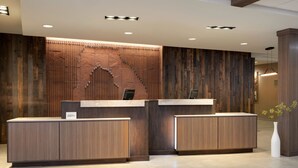 A reception desk with a wooden finish and a modern design, featuring a built-in bench and a small sign. - Fairfield by Marriott Inn & Suites Moab (Moab)