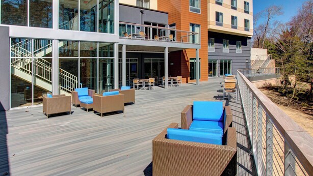 A modern outdoor deck with wicker furniture and a glass railing. - Fairfield Inn & Suites by Marriott Rehoboth Beach (Rehoboth Beach)